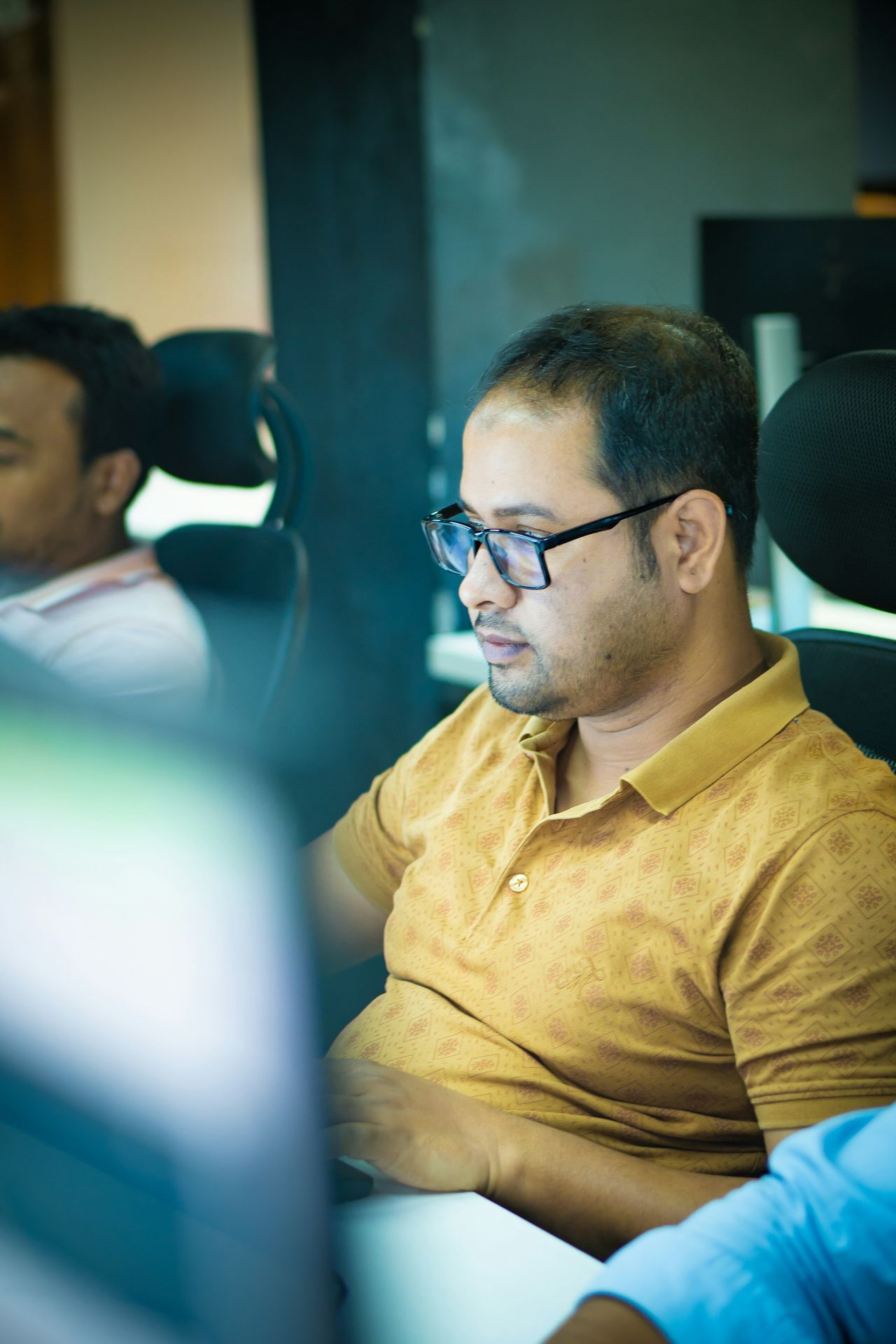 Man wearing glasses works on a computer.